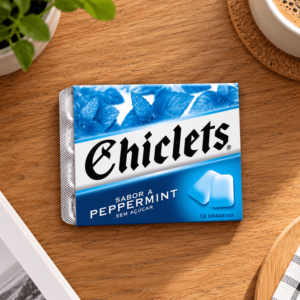 Paquet de chewing-gums Chiclets Peppermint sans sucre, posé à plat sur une table en bois à côté d'une tasse de café.