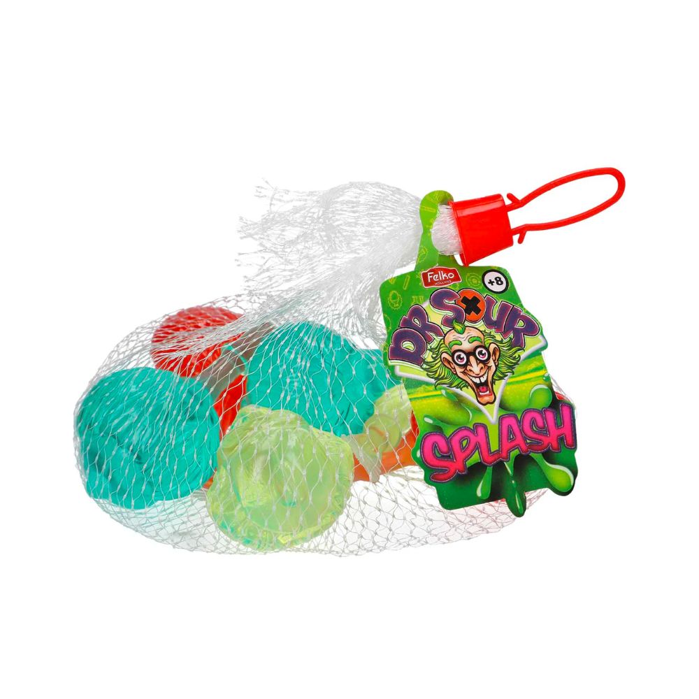 Un emballage en filet qui permet de voir des boules transparentes contenant des liquides de couleurs différentes ; jaune, rouge, bleu et une étiquette verte sur le côté droit avec un visage de Dr aux cheveux verts. Le tout sur fond blanc