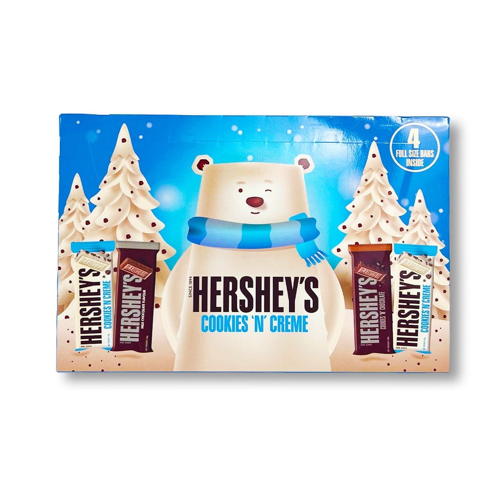 Un carton bleu sur fond blanc avec un immense ours blanc qui fait un clin d’oeil et entouré de 2 sapins blanc. De part et d’autre de l’ours, 4 barres chocolatées