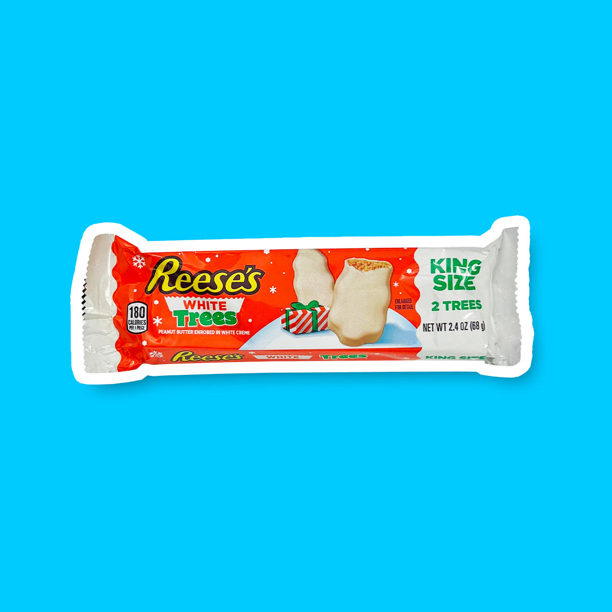 Un emballage orange rectangulaire sur fond bleu, avec des extrémités blanches. Au milieu, il y a des chocolats blancs en forme de sapin et sur le côté droit il est écrit « King Size »