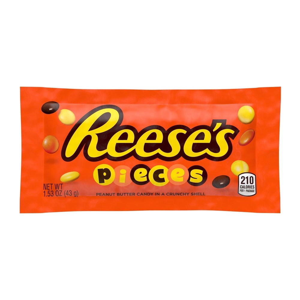 Un emballage orange sur fond blanc avec écrit « Reese’s » en jaune et au centre, autour il y a des petites billes de couleurs différentes : jaune, orange et marron