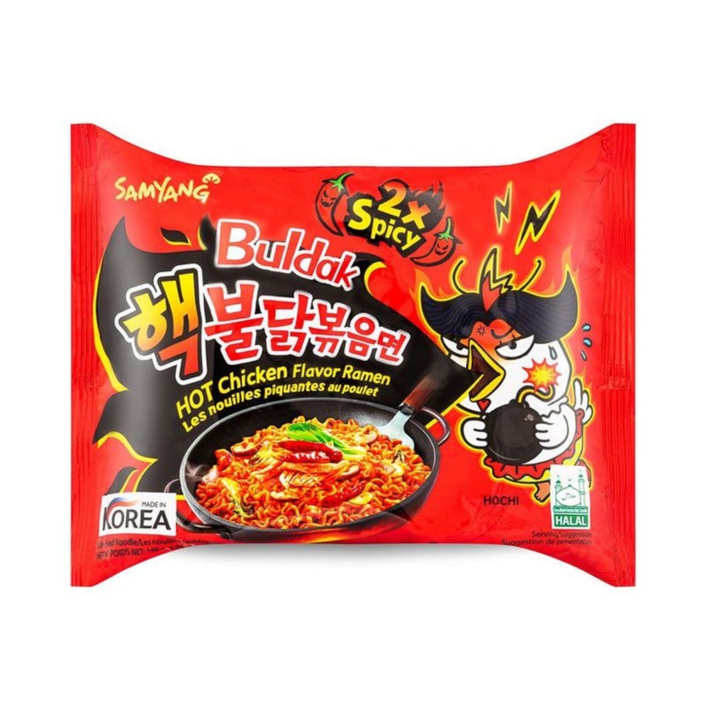 Un petit paquet rouge sur fond blanc avec à droite une petite créature blanche qui crache un feu noir et à gauche une poêle noire de nouilles très rouges