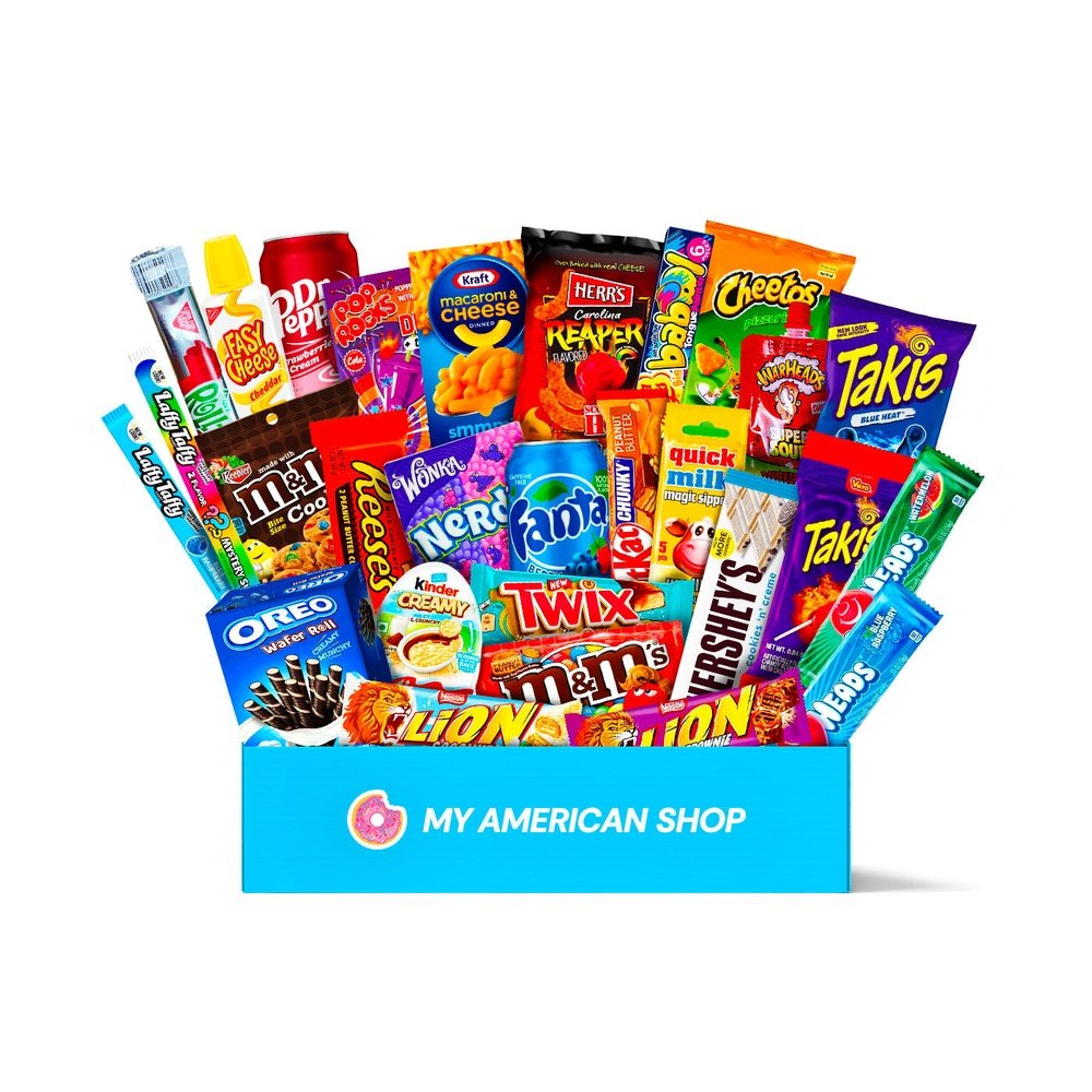 Un très grand carton rectangulaire bleu sur fond blanc contenant une vingtaine de snacks américains sucrés et salés comme des Reese’s, Lion, Takis, Quick Milk vanilla, Dr Pepper, Laffy Taffy, …