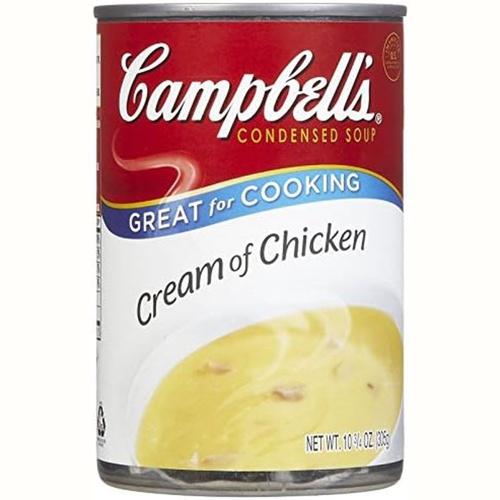 Une boite de conserve rouge sur fond blanc avec un bol blanc de crèmes au poulet chaud de couleur jaune