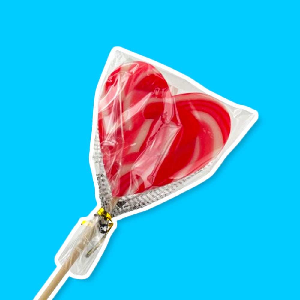 Une sucette rouge et blanche en forme de coeur avec son sachet transparent et un bâton en bois, le tout sur fond bleu