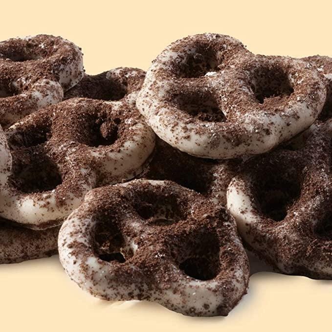 Des bretzels enrobés de chocolat blanc et saupoudrés poudre de cookies au chocolat et entassés les uns sur les autres 