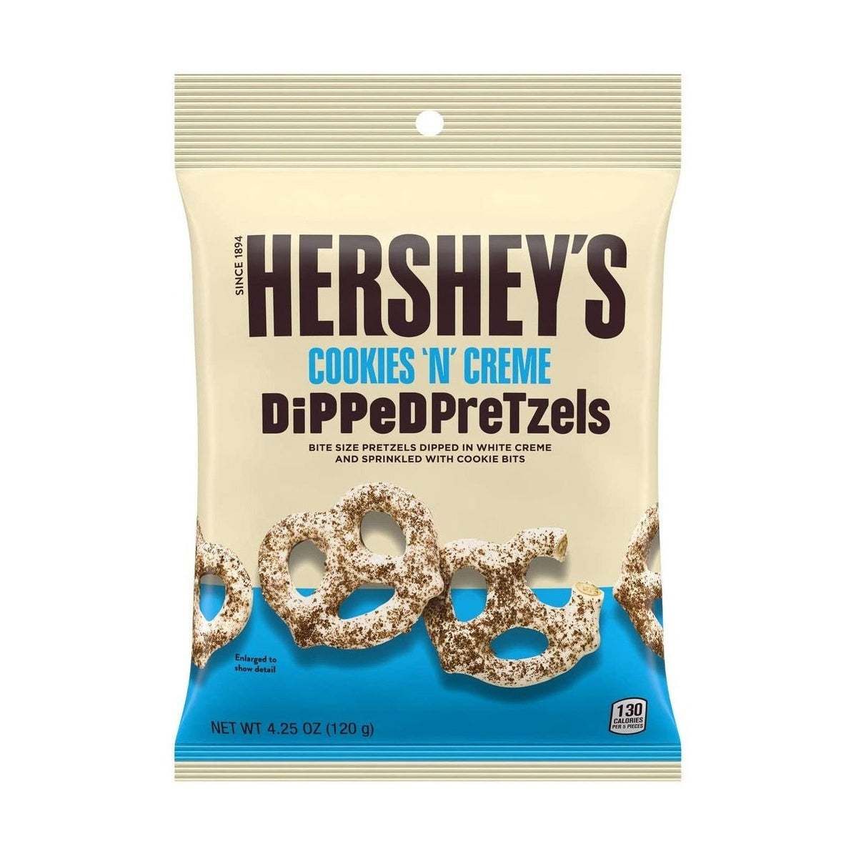 Un emballage beige avec une bande bleu en bas, et des bretzels enrobés de chocolat blanc et saupoudrés poudre de cookies au chocolat, le tout sur fond blanc 