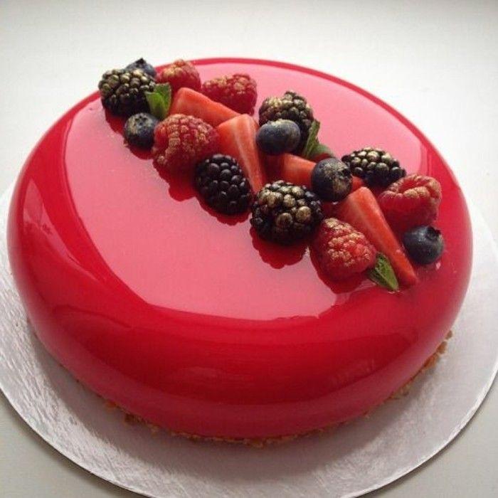 Un gâteau rouge sur une planche grise avec sur le dessus des framboise, fraise et mure 