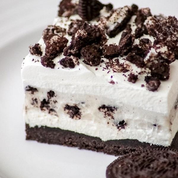 Un cake avec une couche de chocolat et une couche blanche avec des biscuits noirs au-dessus