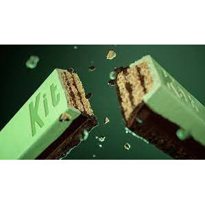 Un biscuit en bâtonnet enrobé de chocolat vert/brun avec des éclats de biscuits autour. Le tout sur fond vert