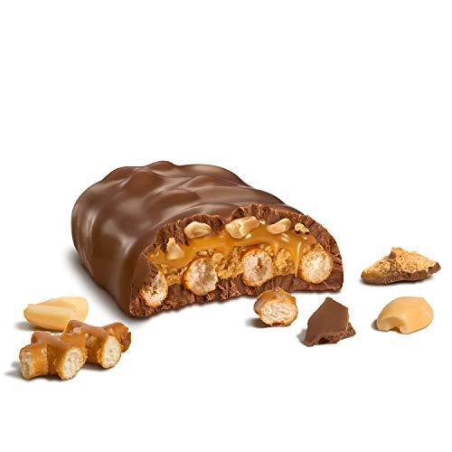 Une barre de chocolat coupé, à l’intérieur on y voit des bretzels, des cacahuètes et du caramel. Le tout sur fond blanc