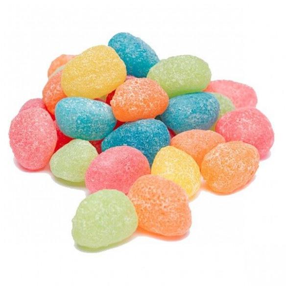 Un tas de bonbons en forme d’haricots acidulés vert, bleu, rouge, orange et jaune. Le tout sur fond blanc